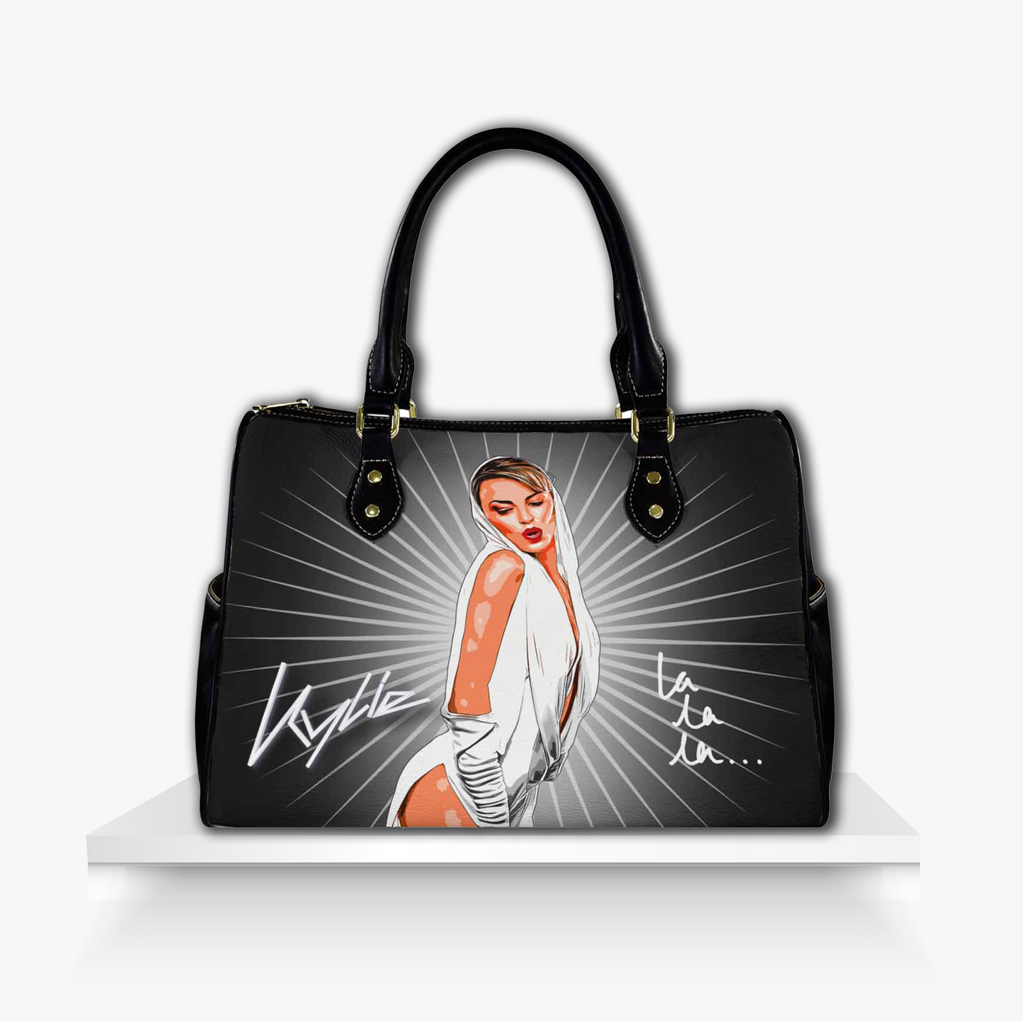 Black barrel-style handbag featuring a bold illustrated portrait of Kylie Minogue in a glamorous white outfit with radiant silver beams, her signature, and the iconic 'la la la...' lyric stylish pop star fashion accessory perfect for Kylie fans, dance-pop lovers, and standout glam looks