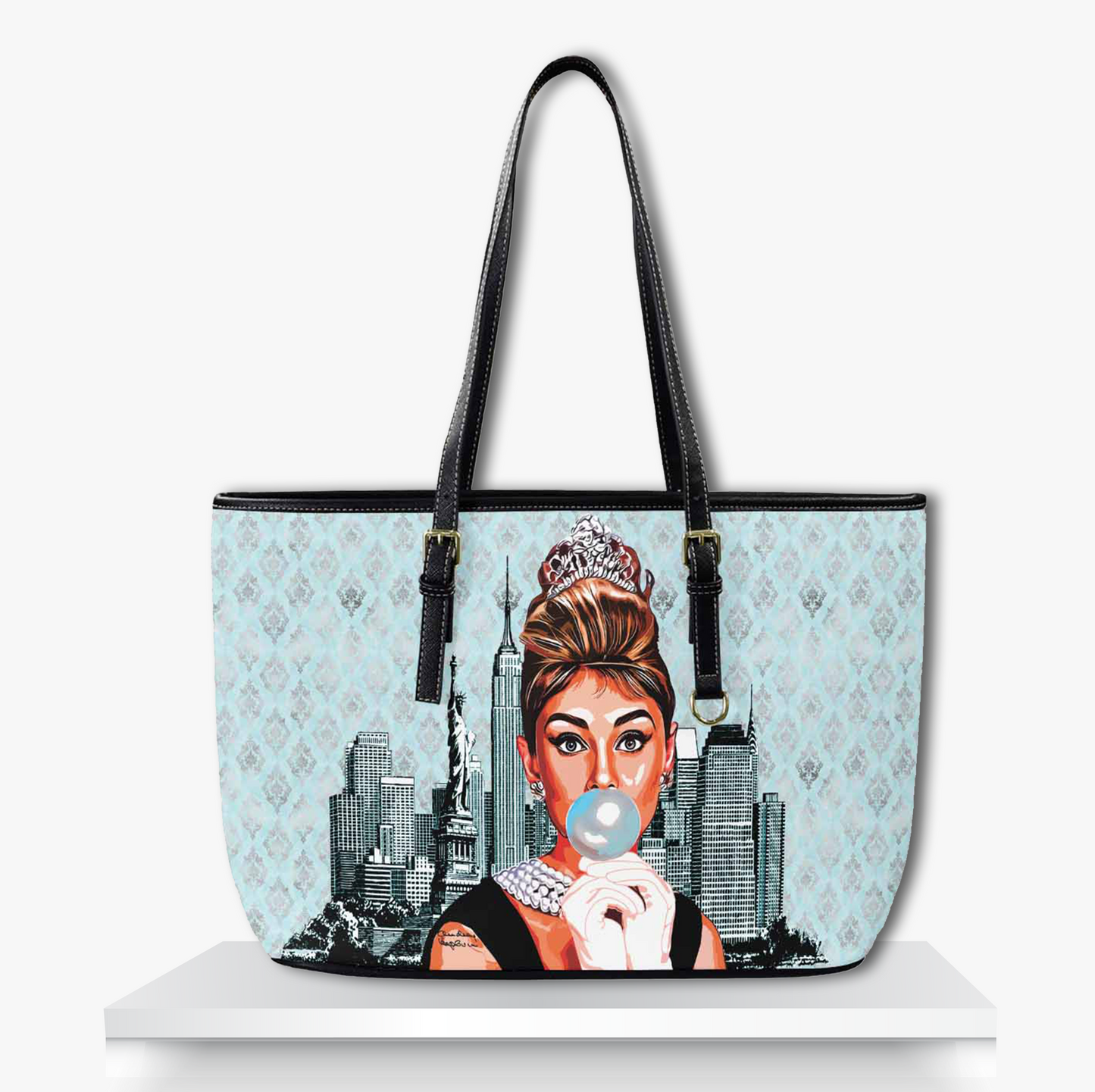 Elegant light blue tote bag featuring a modern illustrated portrait of a glamorous woman styled like Audrey Hepburn, wearing pearls and a tiara while blowing bubble gum set against a vintage damask pattern and New York City skyline. Perfect for fans of classic Hollywood fashion with a playful pop art twist.